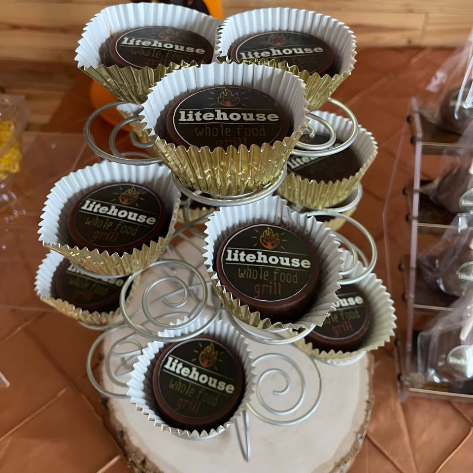 A tiered display stand holds Litehouse Whole Food Grill branded chocolate candies in gold and white wrappers.